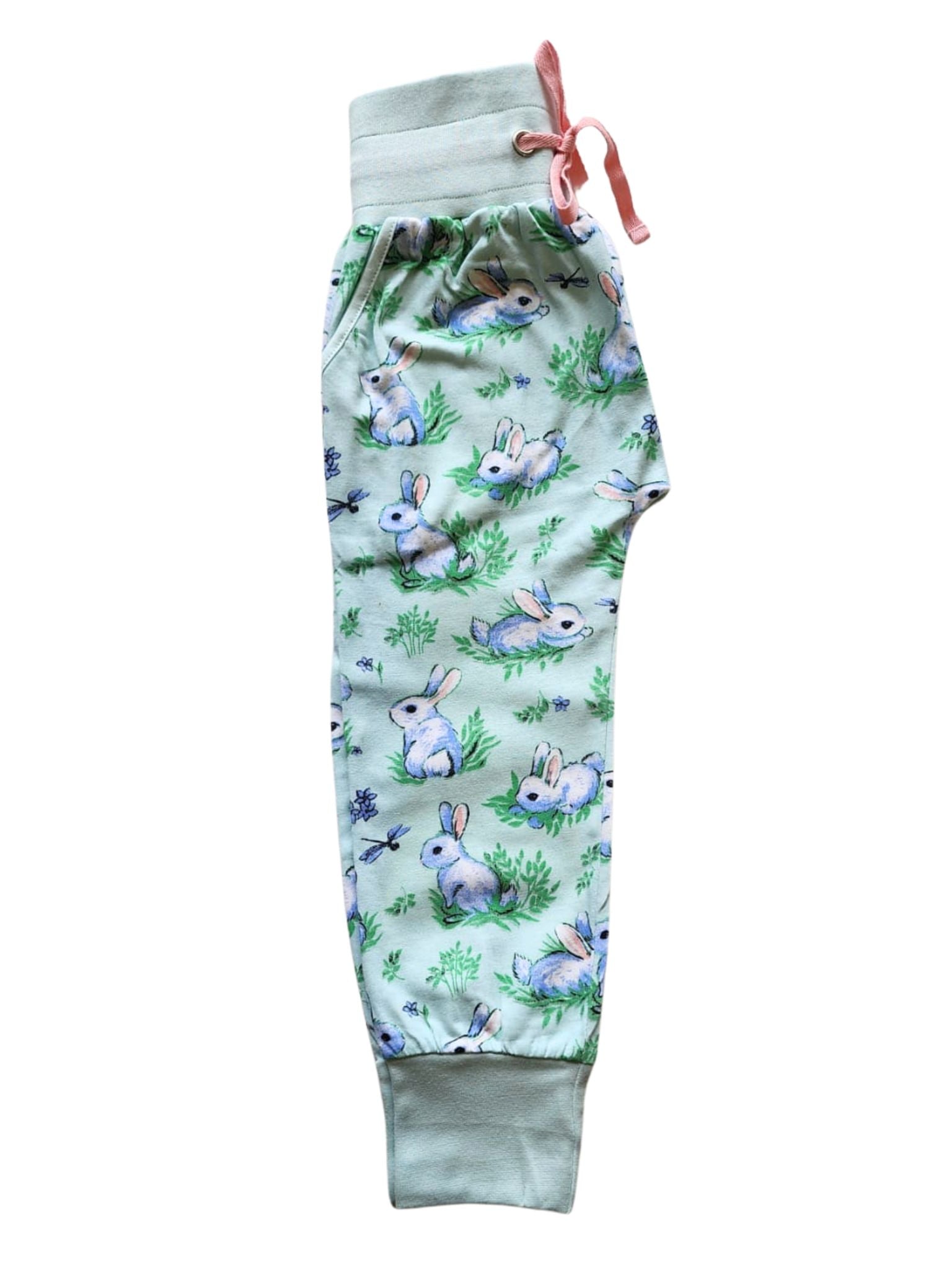 The Blue Bun-Buns Soft Jersey Pants by Bun-Buns feature a bunny and foliage pattern, a green elastic waistband, and a pink drawstring. Made from soft jersey fabric, they promise ultimate comfort and style.