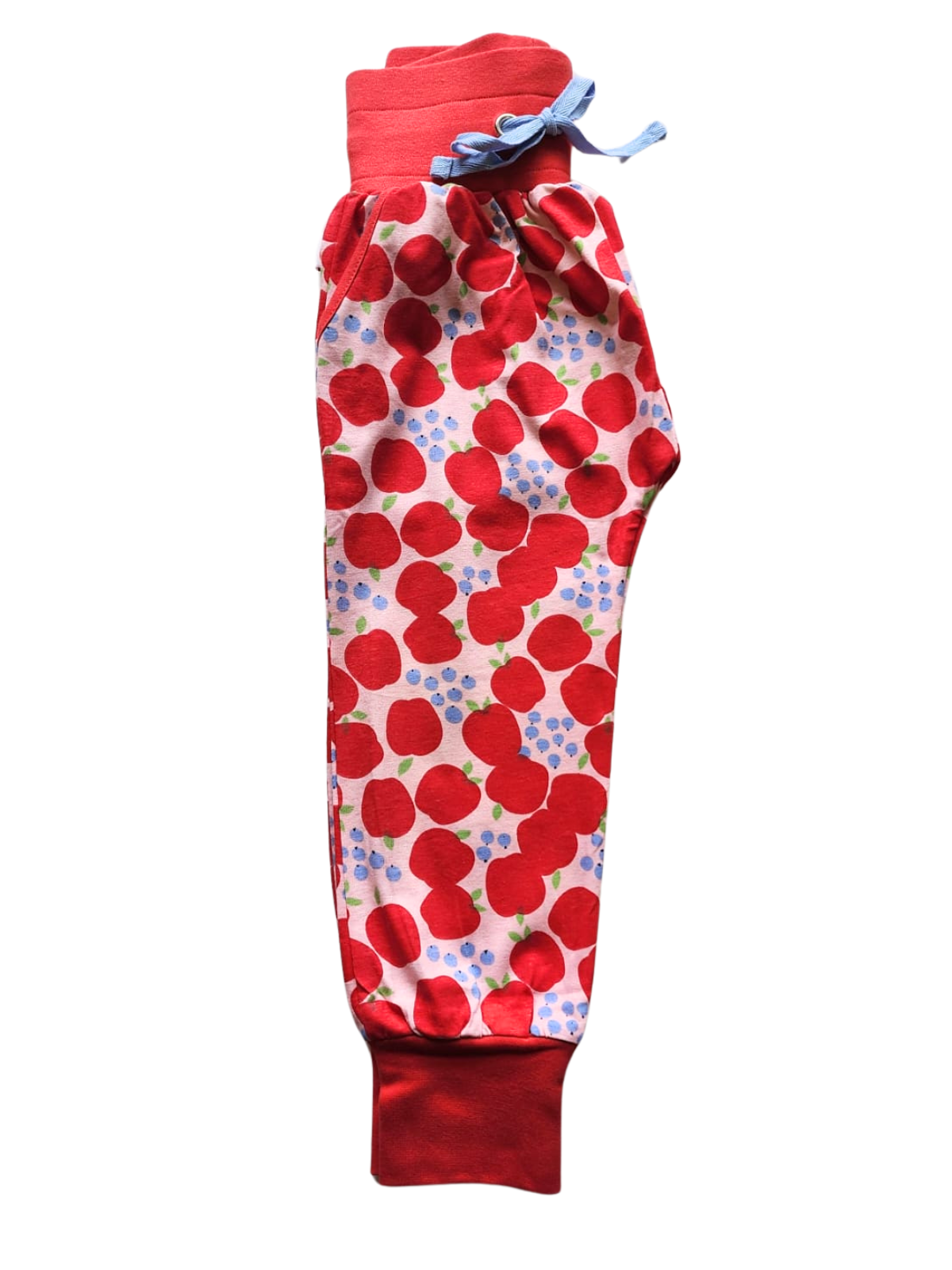 The Sweet Apple Soft Jersey Pants, boasting a charming apple pattern with a blue bow at the elastic waist, are crafted for comfort from soft fleece. This best-seller from Sweet Apple combines style and coziness beautifully in its red and white design.