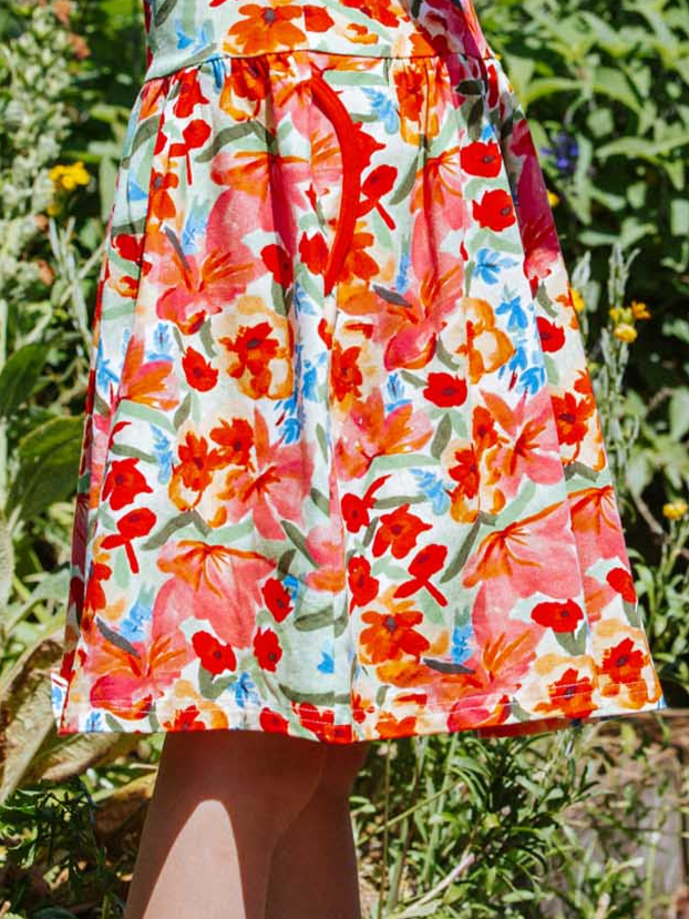 A person wearing the Wild Roses Amelie Dress stands outside near lush greenery.