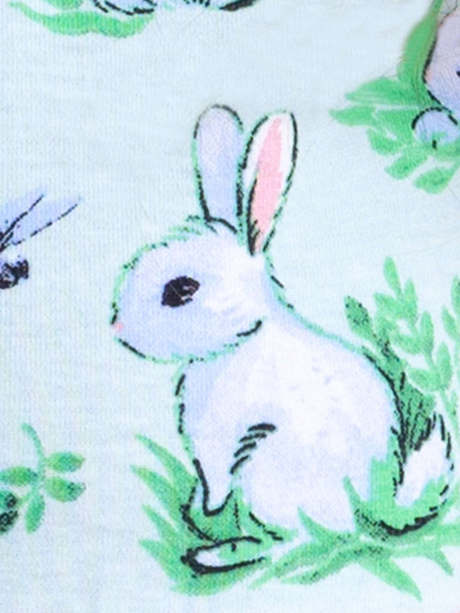 Illustration of an adorable bunny from the Blue Bunnies Ariel Dress collection by Bunny, sitting on grass and surrounded by green foliage, set against a light background.