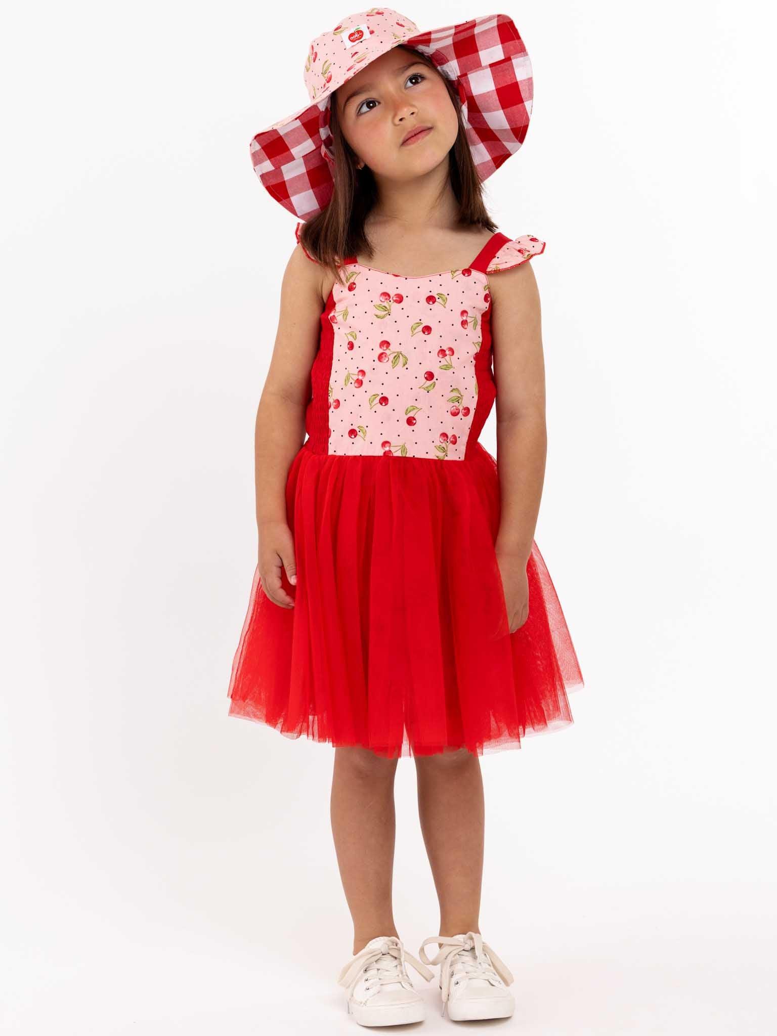 A little girl wearing a red dress and hat.