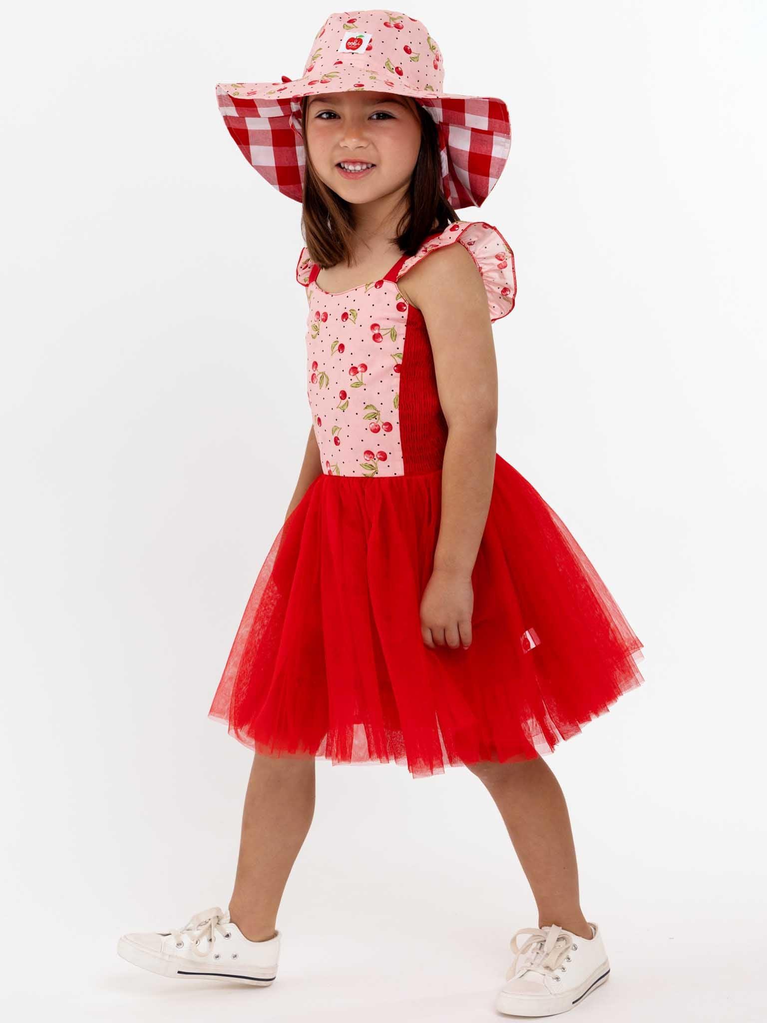 A little girl in a red Cherry Ripe Belle Tutu Dress and hat by Retro Cherry.