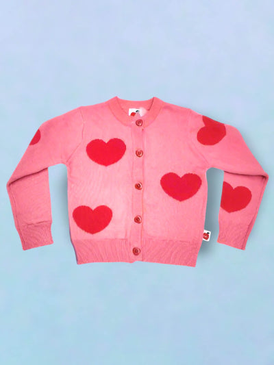 The Light and Dark Pink Heart Maxine Cardigan by Knitwear showcases charming pink heart patterns with delightful heart-shaped buttons, all on a light blue cotton cable knit background.