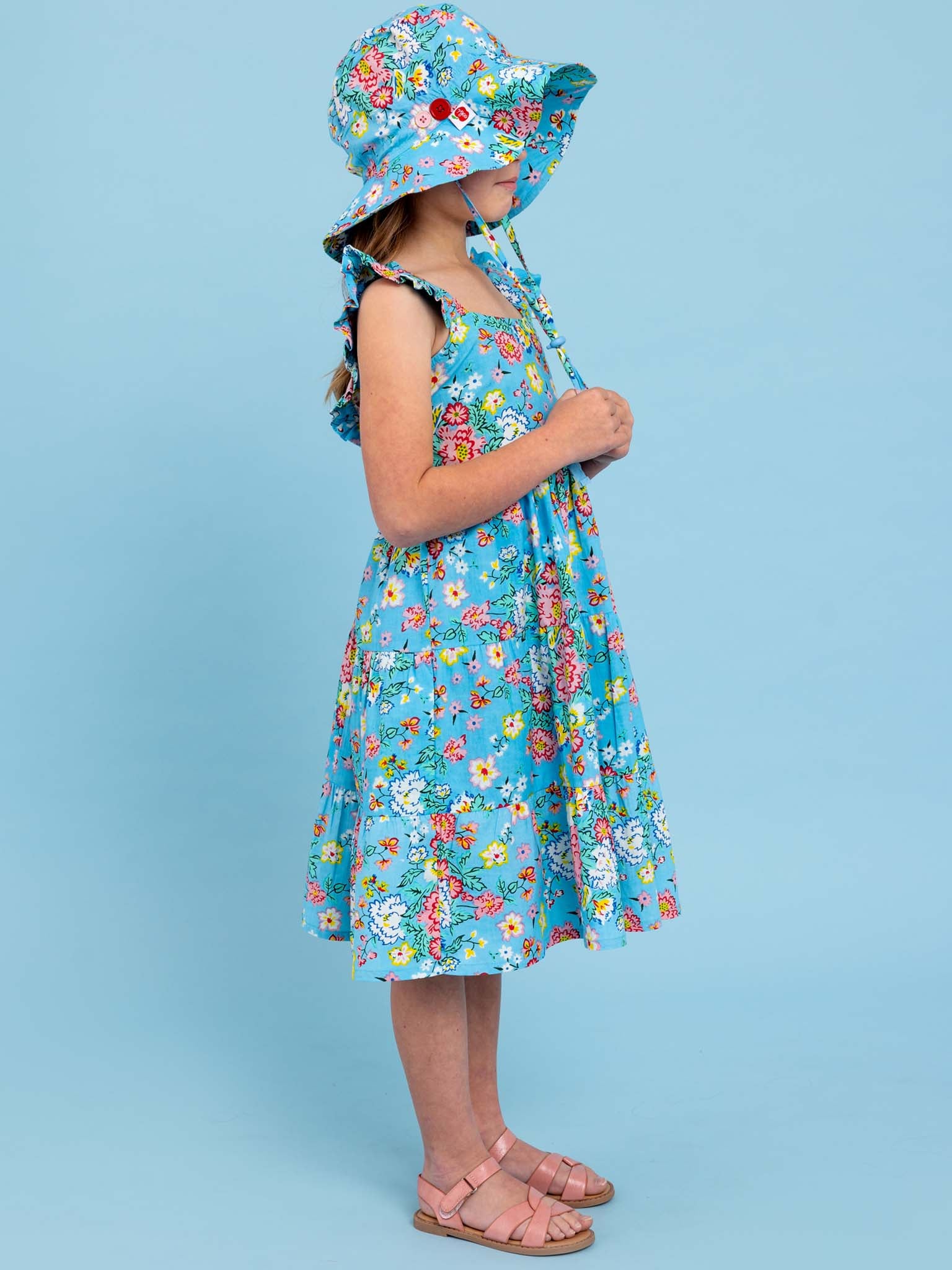 A little girl wearing a beloved Cornflower Meadow Midi-Maxi Dress with hat.