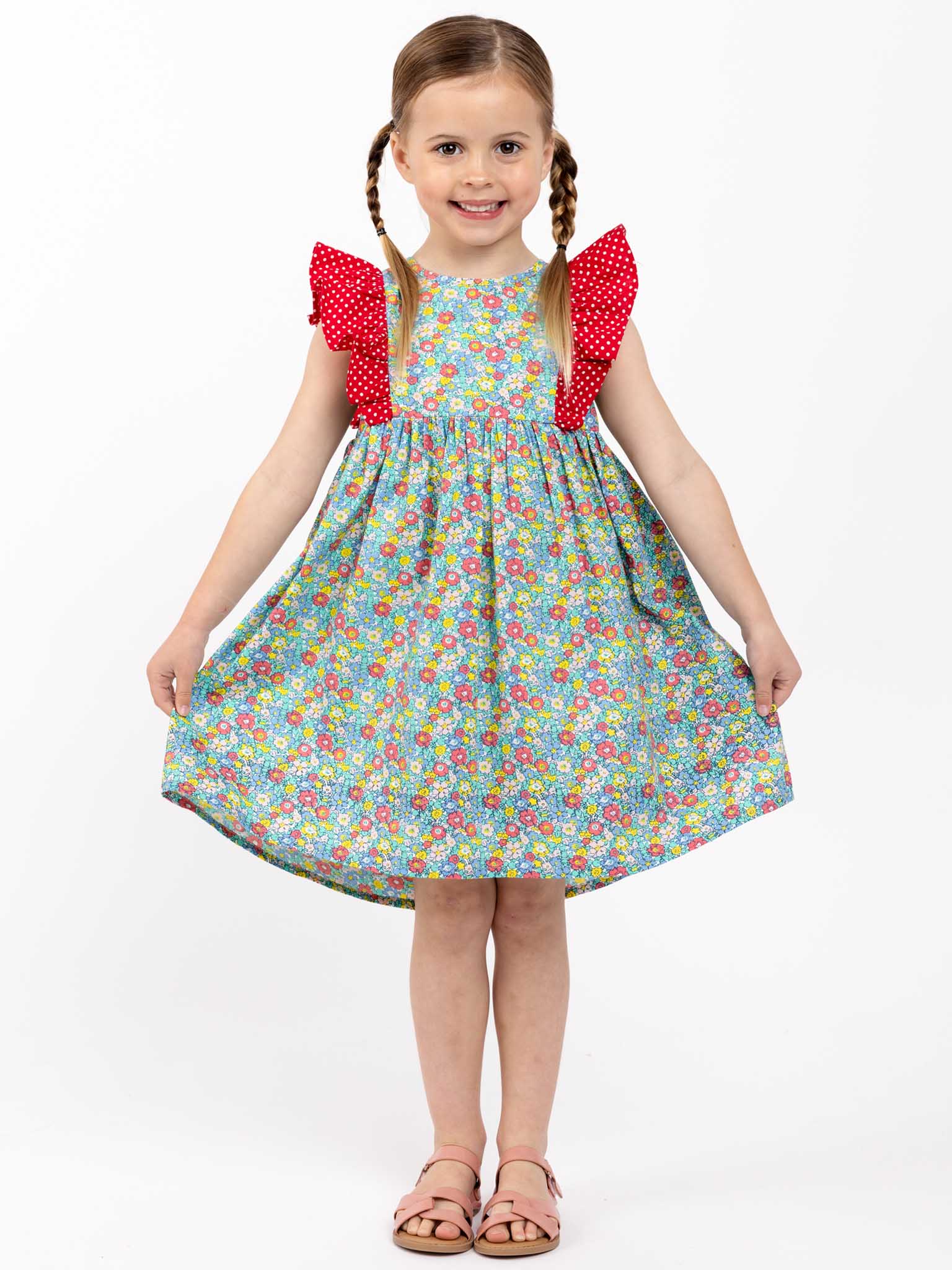 A little girl wearing a New Minifloral Molly Minifloral Dress with ruffle sleeves.