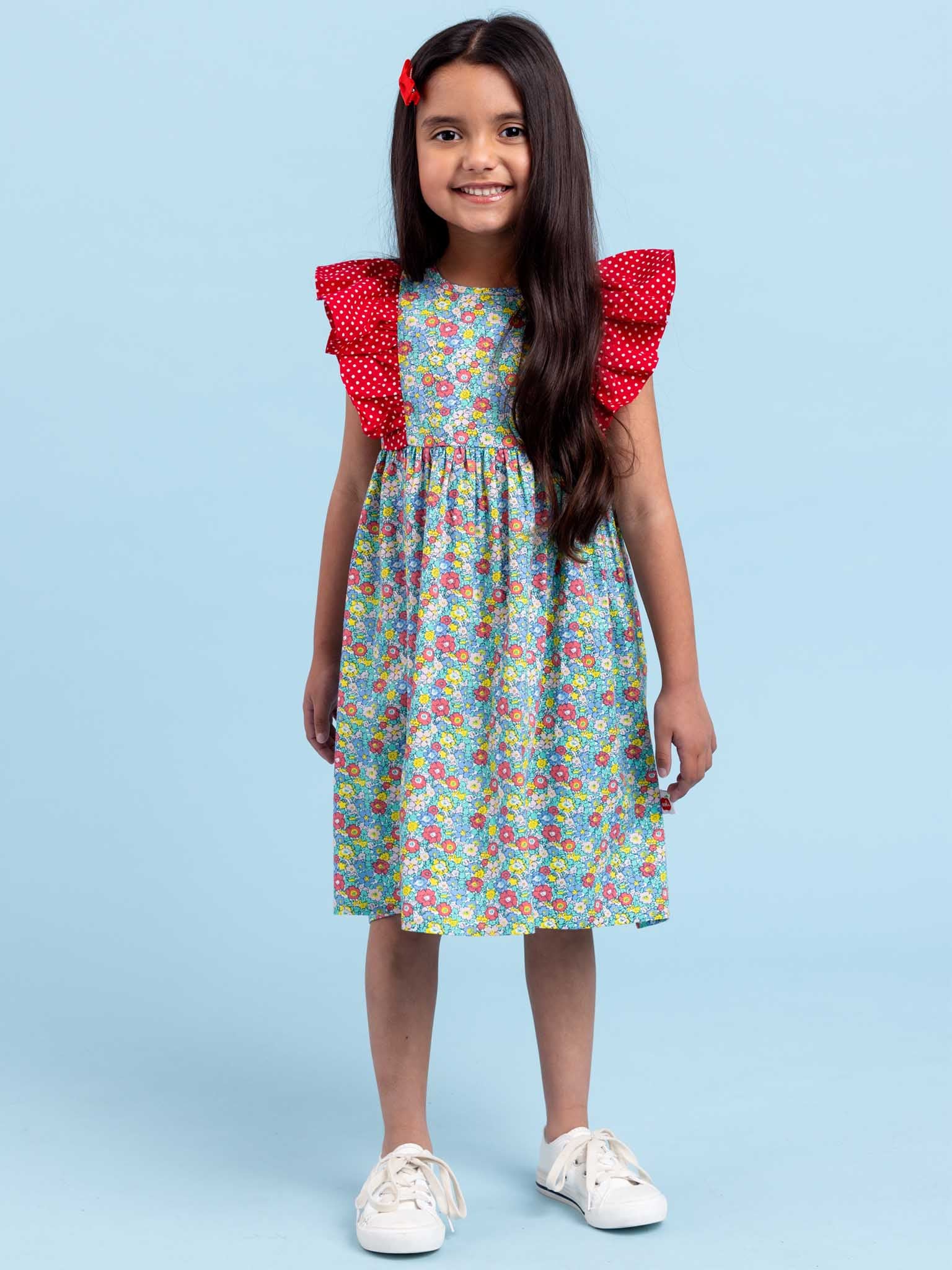 A little girl in a Molly Minifloral Dress by New Minifloral with ruffle sleeves for summer.