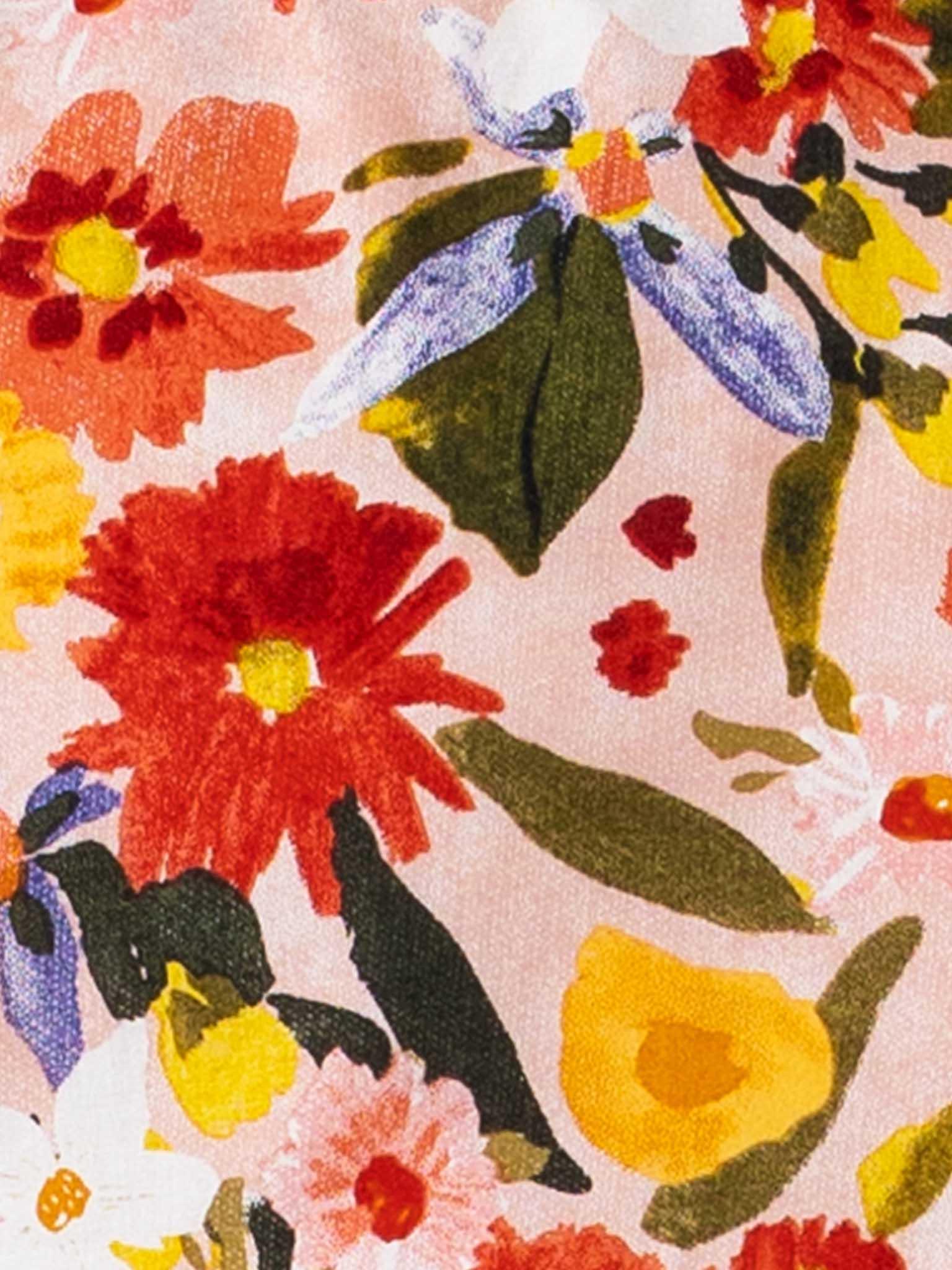 Close-up of a Native Bloom dress with a pattern of colorful flowers on a pink background, suitable for a little girl dress.