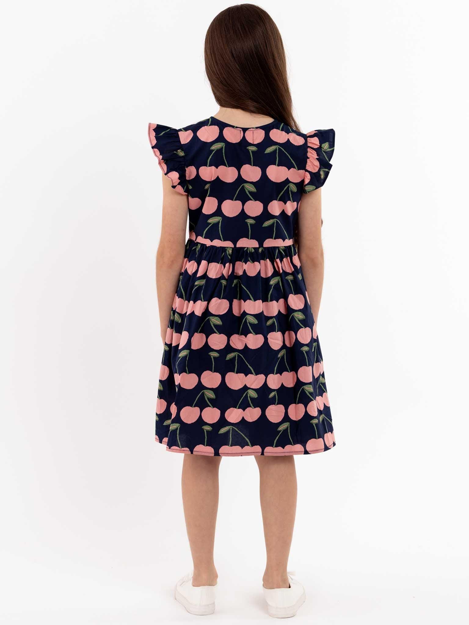 A girl wearing a Navy Cherry Madison dress with cherries on it - COMING 1ST WEEK OCTOBER.