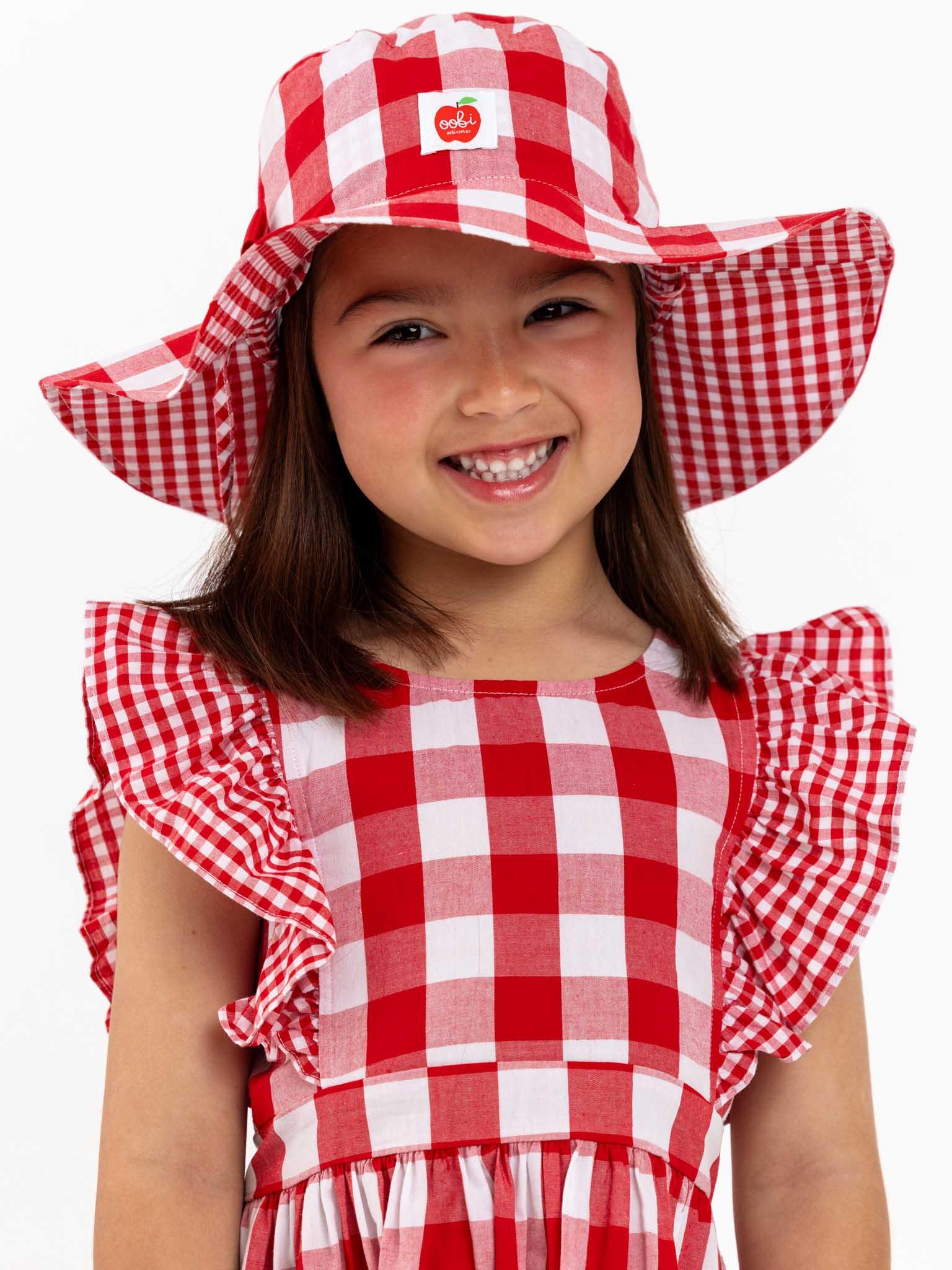 A little girl wearing an oversized ruffle sleeve Red Check Jayne dress with a gingham waistband from the brand Red Check.