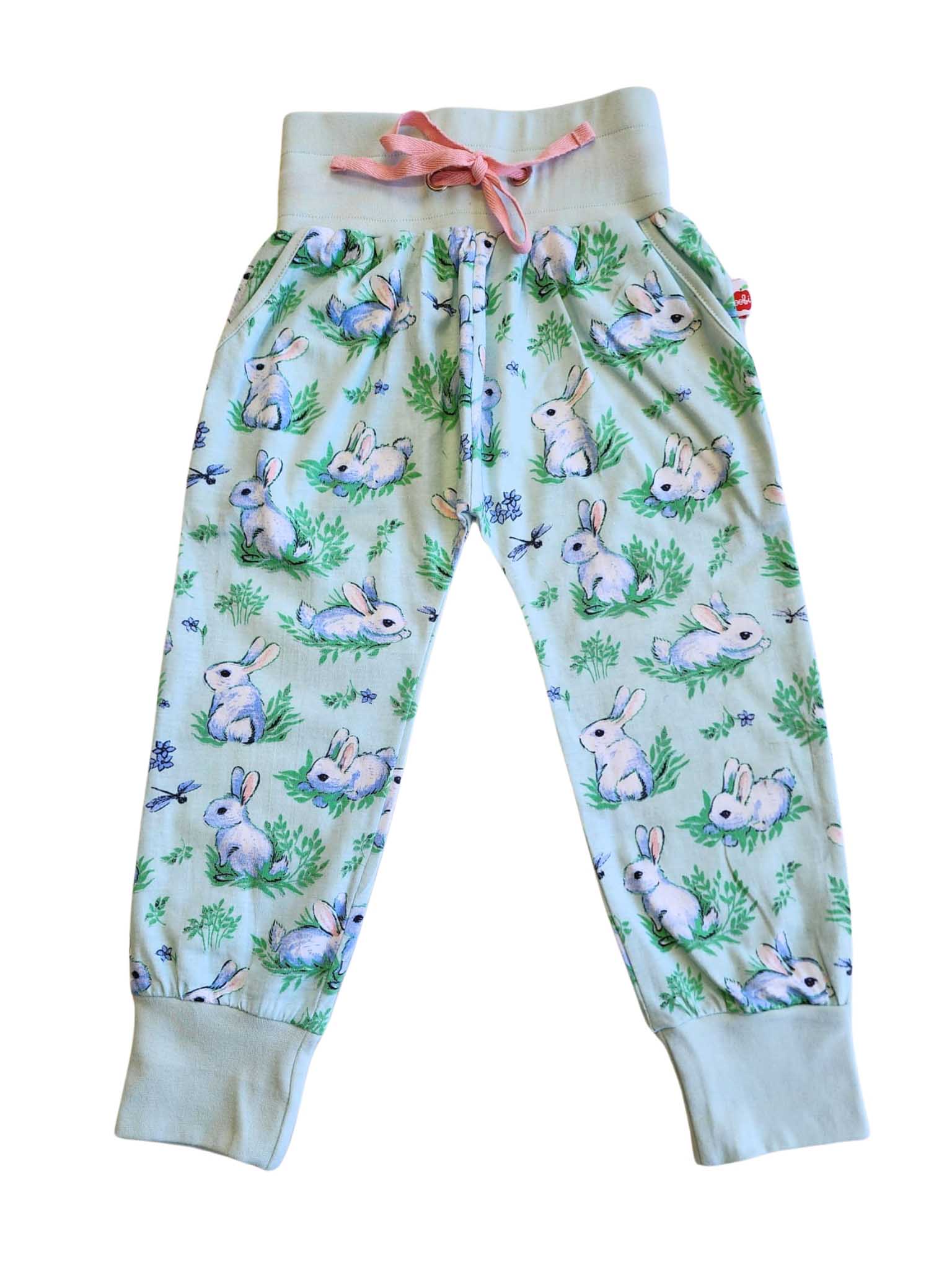 The top-selling Blue Bun-Buns Soft Jersey Pants by Bun-Buns are light blue, featuring an elastic waist, pink drawstring, and a cute rabbit and green foliage pattern. Pair with the Zadie Jacket for an adorable outfit.