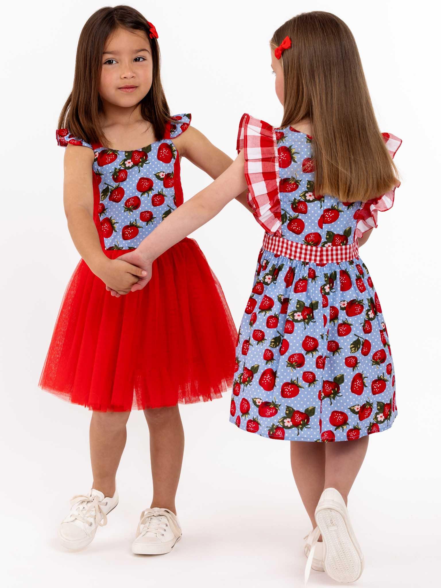 Two little girls twirl approved in blue and red cotton bodice dresses, with Strawberry Fields Belle Tutu Dress.