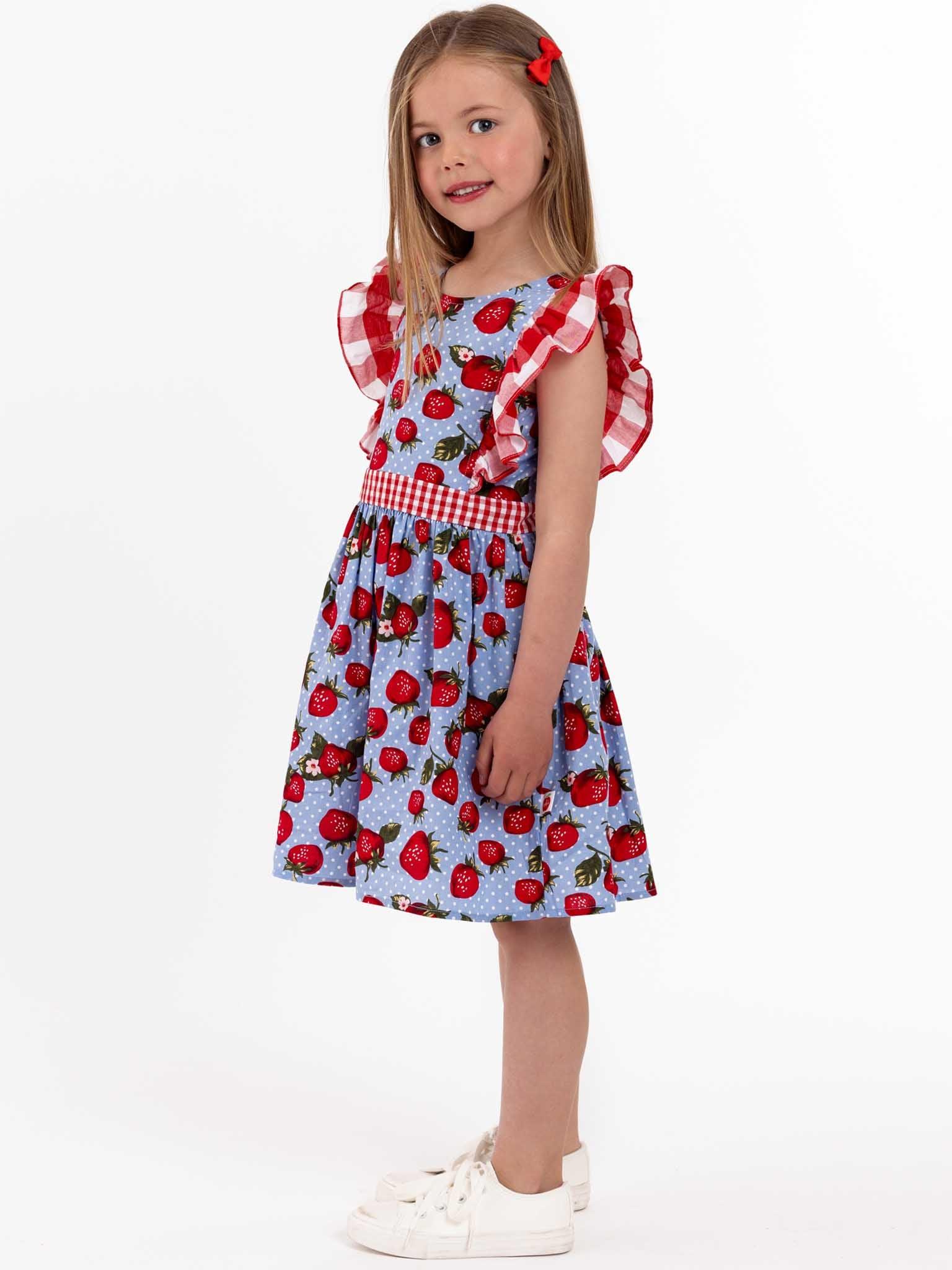 A little girl wearing a Strawberry Fields Jayne dress with strawberries on it.