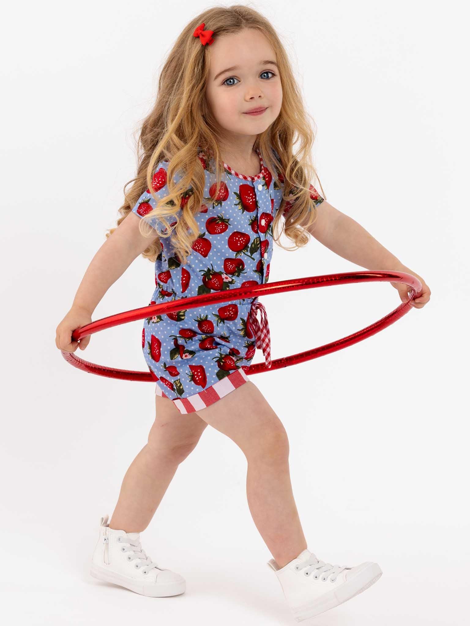 A little girl playing with a Strawberry Fields Maisy Playsuit, an easy-to-wear hula hoop.