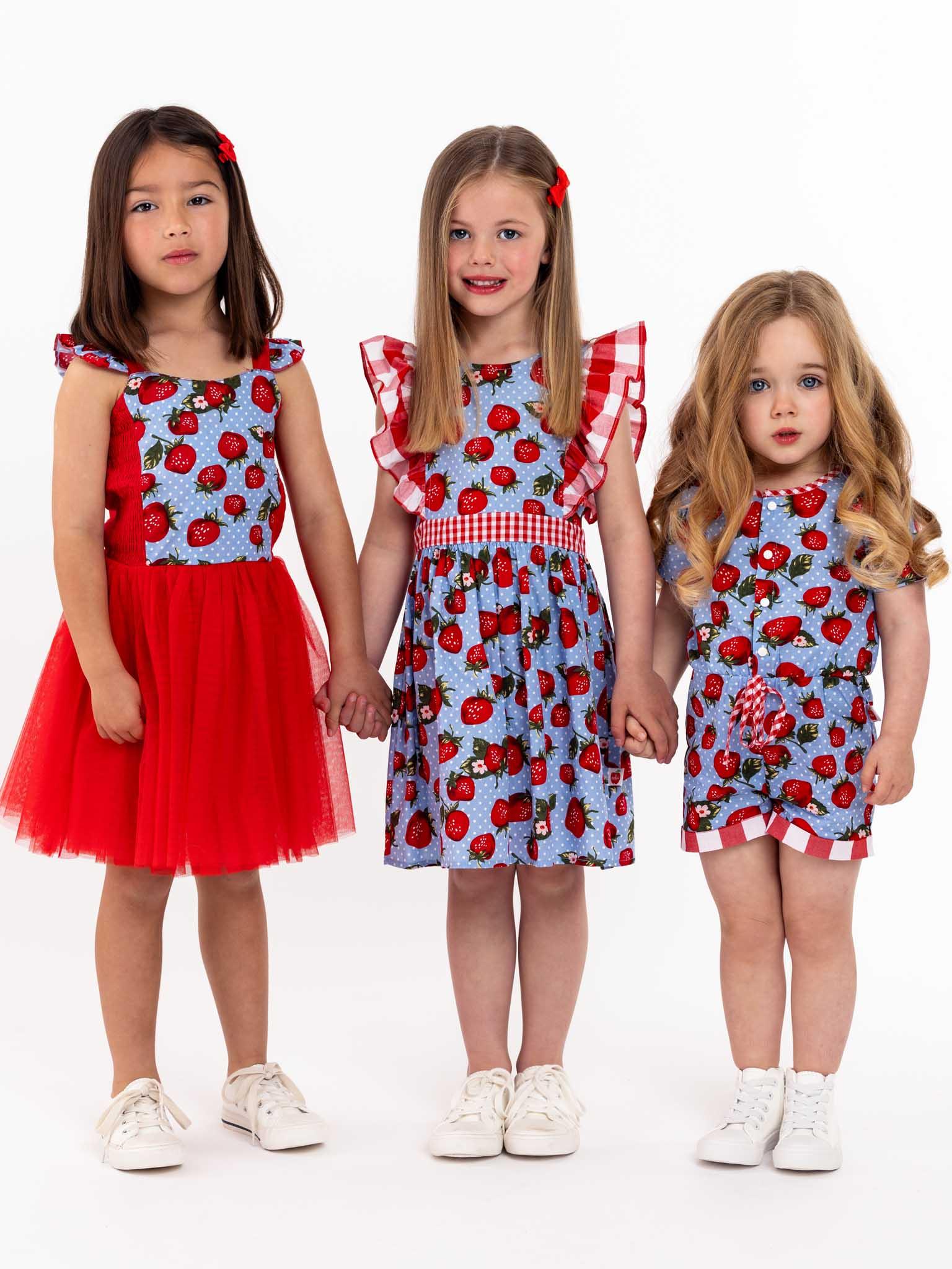 Three little girls in Strawberry Fields Maisy Playsuits standing next to each other.