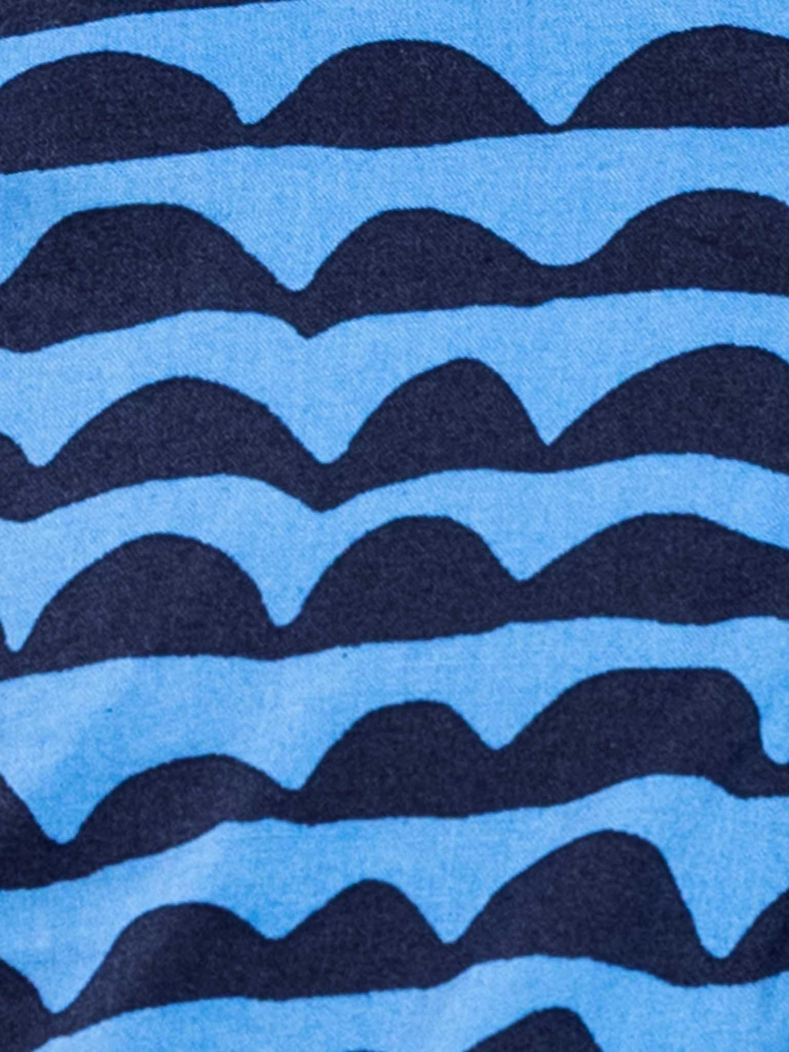 Close-up of a fabric pattern featuring alternating dark blue and light blue wavy stripes with a crochet fruity feature on the Wiggly Ocean Blue Adriana Dress by Wiggly.